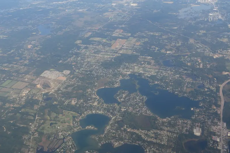 Highland Township from above: wooded parcels and open ground side by side, the mix much of north Oakland County has.